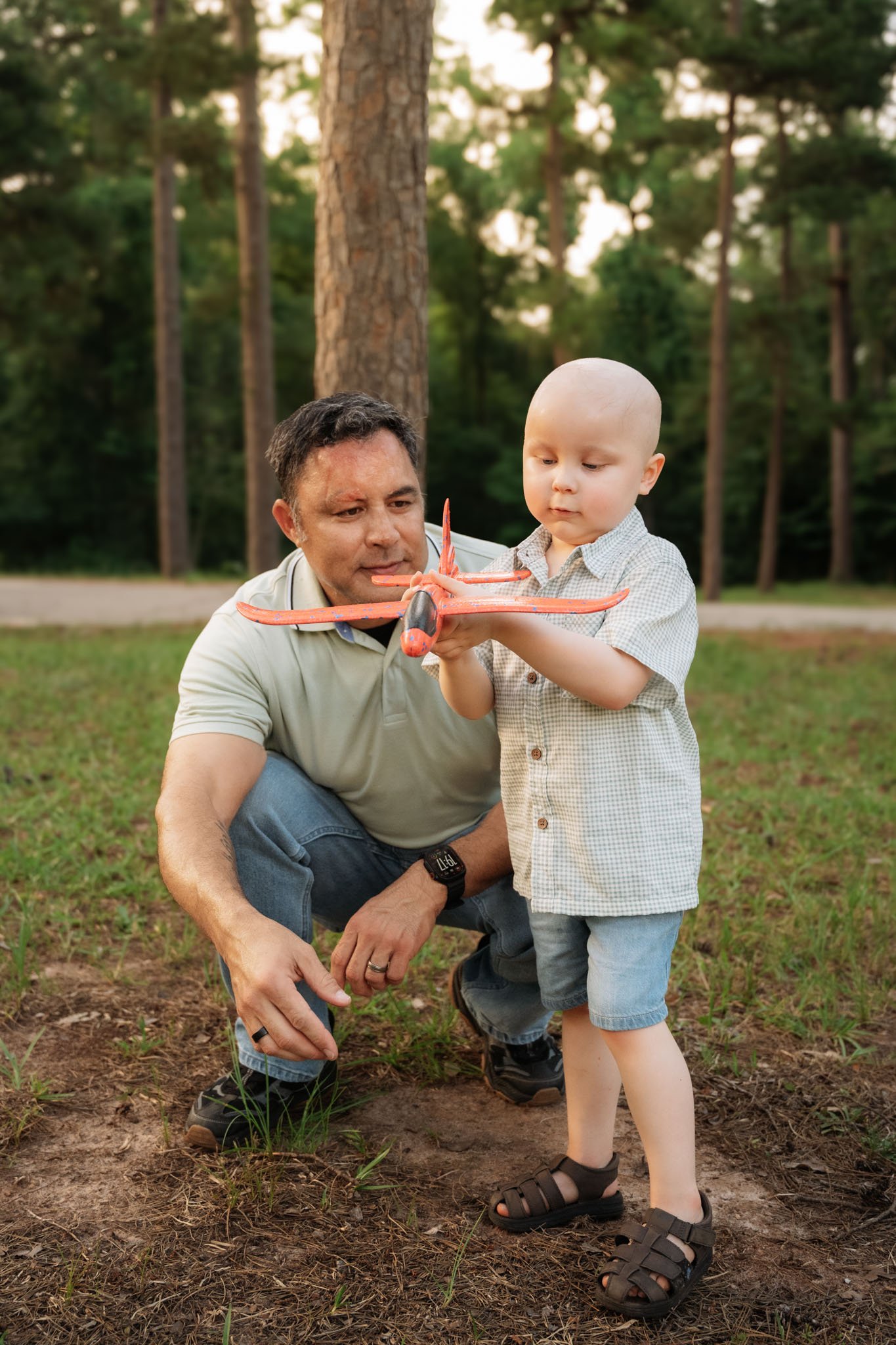 father and son play with model planes in the park